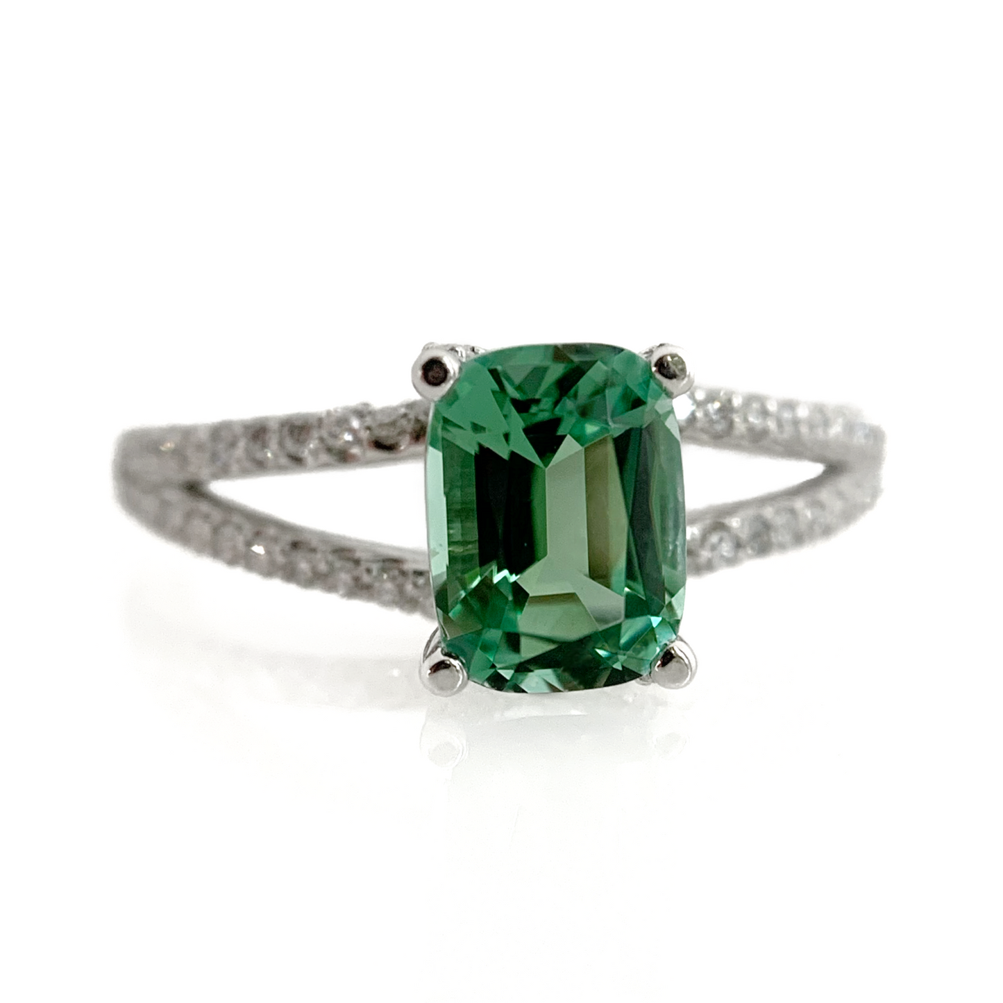 Featuring a glowing, cushion cut, blue-green tourmaline set in a trellis style setting with bead set diamonds flowing from the top of the prongs down the shank. Finger Size: 8 (Can be resized at no additional cost, just ask!) Stone: 1.46ct Natural Blue Green Tourmaline; 0.32ctw Diamonds, G-H, VS Metal: 14k White Gold Handmade by Meg C
