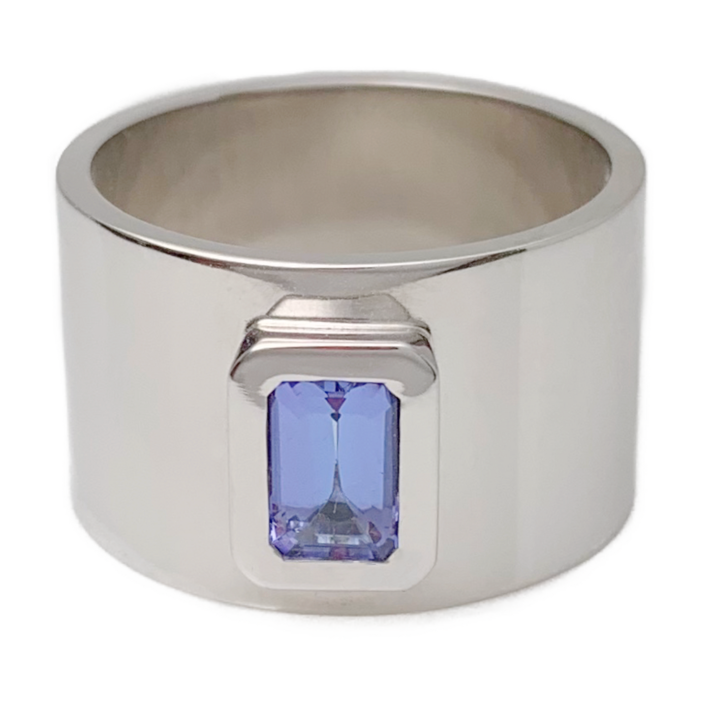 Featuring a bright, beautiful, emerald cut Tanzanite, bezel set in a wide white gold band. Size: 6 Dimensions: 12mm wide band Stone: .056ct emerald cut Tanzanite Metal: 14k White Gold Handmade by Meg C