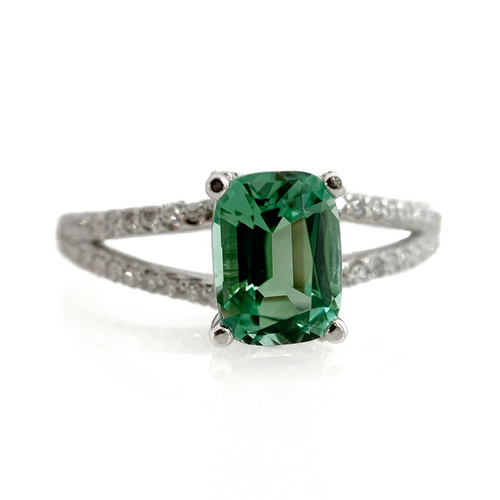 Featuring a glowing, cushion cut, blue-green tourmaline set in a trellis style setting with bead set diamonds flowing from the top of the prongs down the shank.  Finger Size: 8 (Can be resized at no additional cost, just ask!) Stone: 1.46ct Natural Blue Green Tourmaline; 0.32ctw Diamonds, G-H, VS Metal: 14k White Gold Handmade by Meg C
